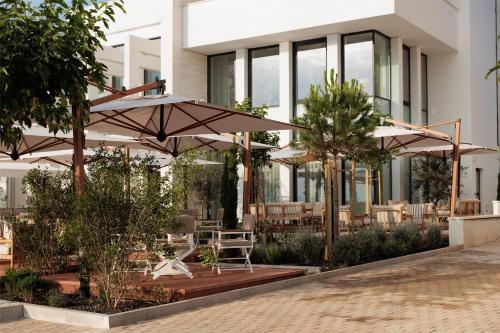 a building with tables and umbrellas in front of it at Hotel Preko Ugljan Island, Curio Collection By Hilton in Preko
