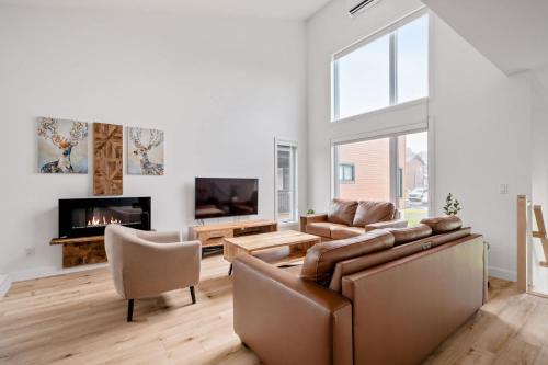 a living room with a couch and a tv at Ski and Spa - L'Altitude des Sommets in Stoneham