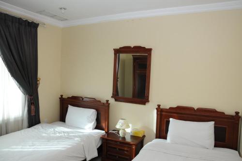 a bedroom with two beds and a mirror on the wall at Arinza Tower Quality Apartments in Kuwait