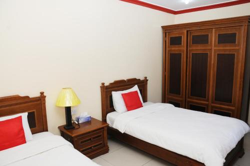 a bedroom with two beds and a lamp on a night stand at Arinza Tower Quality Apartments in Kuwait