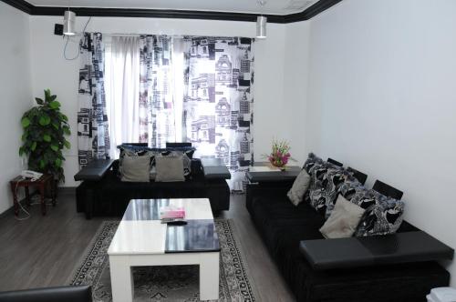 uma sala de estar com um sofá preto e uma mesa em Arinza Tower Quality Apartments em Kuwait