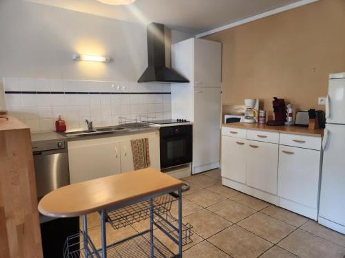 a kitchen with white appliances and a table in it at Gîte La Fontaine 