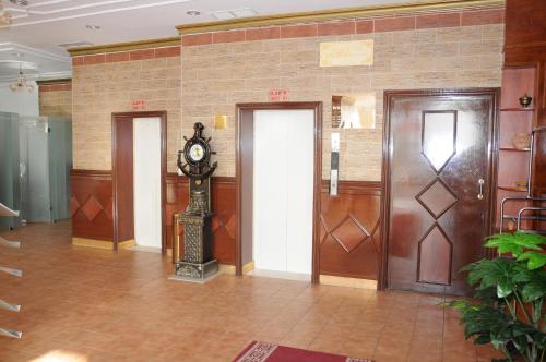 a lobby with three doors and a clock in the middle at Arinza Tower Quality Apartments in Kuwait