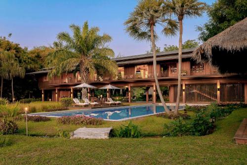 a resort with a swimming pool and palm trees at Tatvani Thailand - Private All-Inclusive Estate in Chiang Rai