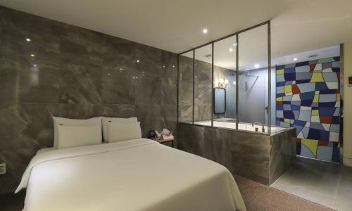 a bedroom with a white bed and a bath tub at Hotel H2 in Ulsan
