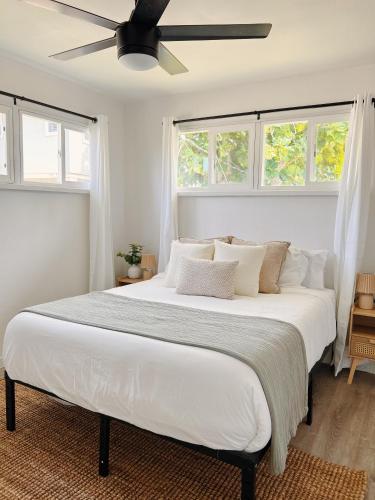 a bedroom with a large white bed with a ceiling fan at Hale Moana Retreat AC Walk to Ocean and Spacious Family Stay in Laie