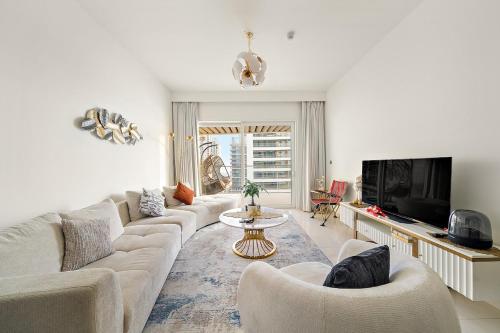 a living room with a couch and a tv at Beachfront 2BR Grand Bleu Luxe Near Dubai Palm & Marina Hotspots in Dubai