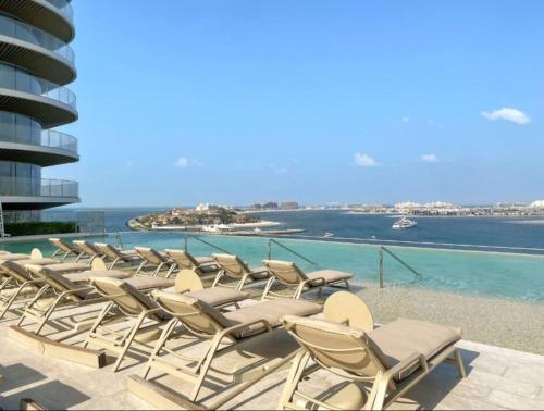 a row of chaise lounge chairs on a swimming pool at Beachfront 2BR Grand Bleu Luxe Near Dubai Palm & Marina Hotspots in Dubai