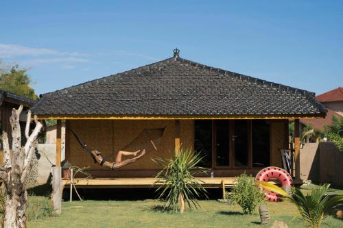 a person in a hammock in a house at Baha Baha Villas West Sumbawa Yoyos Wellness Center, Gym, Yoga, Skate Park, Bar & Cafe in Sekongkang