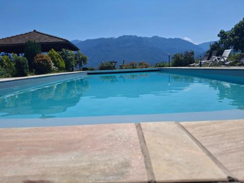 une piscine avec de l'eau bleue et des montagnes en arrière-plan dans l'établissement LA GRANGE BONAL, à Villette