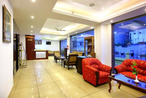 a living room with red chairs and a table at Hotel Indraprastha Kayamkulam in Pattiyūrgrāmam