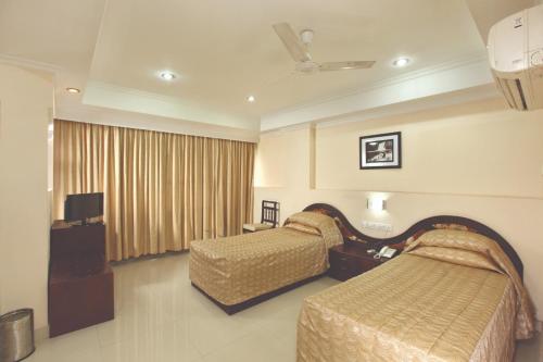 a hotel room with two beds and a television at Hotel Indraprastha Kayamkulam in Pattiyūrgrāmam