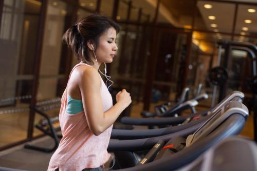 a woman running on a treadmill in a gym at Cheery Dragon Canal Hotel Hangzhou - Intangible Cultural Heritage Hotel in Hangzhou