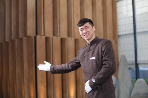 a man is standing in front of a wooden wall at Cheery Dragon Canal Hotel Hangzhou - Intangible Cultural Heritage Hotel in Hangzhou