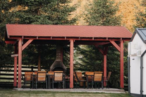 a gazebo with tables and chairs and a bell at Szépasszony Guest House in Vlăhiţa