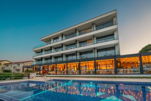 a hotel with a swimming pool in front of a building at Hotel Villa Margaret in Malinska