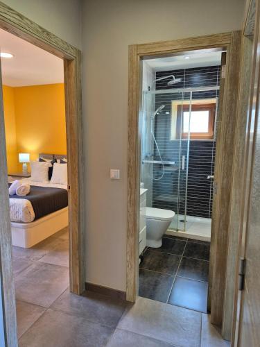 a bathroom with a shower and a toilet and a bed at A Luz do Faro in Muxia