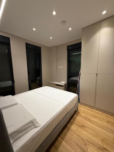 a bedroom with a large white bed and wooden floors at ABC Apartments in Korçë