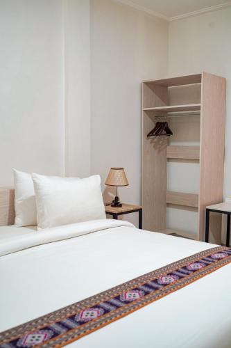 a bedroom with a white bed and a closet at Mama Komodo Bed & Breakfast in Komodo Labuan Bajo Airport