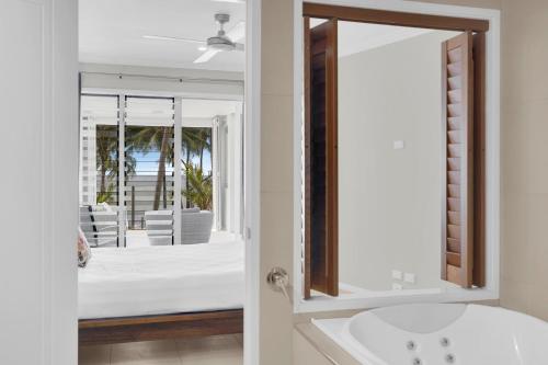 a bathroom with a white tub and a mirror at Seascape Solace - Breezy Waterfront Bliss in Palm Cove