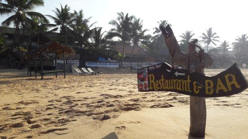 a sign for a restaurant and bar on a beach at Whitepearl Beach in Hikkaduwa