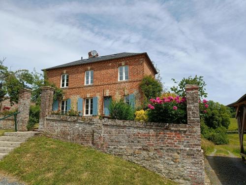 a brick house with flowers on a brick wall at La Daubinière in Saint-Ouen-le-Pin