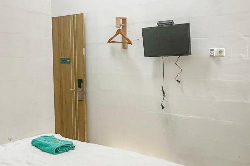 a room with a bed with a tv on the wall at RedDoorz near Universitas Hasanuddin Makassar in Makassar
