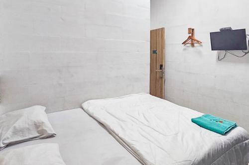 a room with a bed with a tv on the wall at RedDoorz near Universitas Hasanuddin Makassar in Makassar