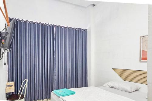 a bedroom with a bed and a blue curtain at RedDoorz near Universitas Hasanuddin Makassar in Makassar