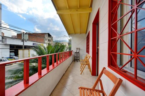 een balkon met rode en witte leuning en stoelen bij The Wandering Paisa in Medellín