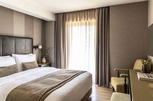a bedroom with a bed and a desk and a window at The Y Hotel in Athens