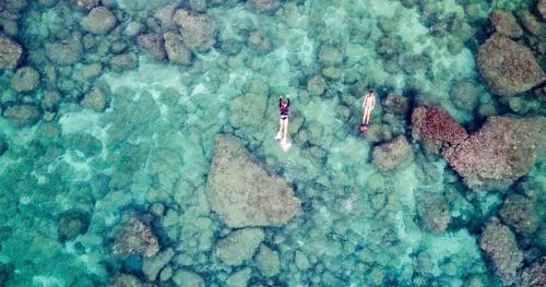 two people standing on rocks in the ocean at Hale Moana Retreat AC Walk to Ocean and Spacious Family Stay in Laie