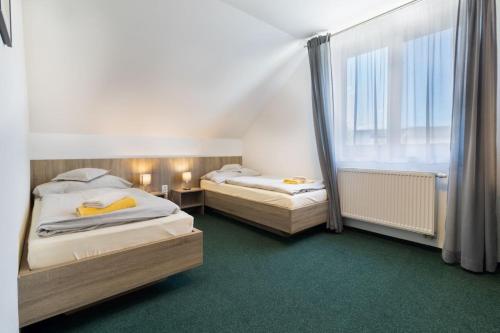 two beds in a small room with a window at Farma Moulisových in Nezvěstice