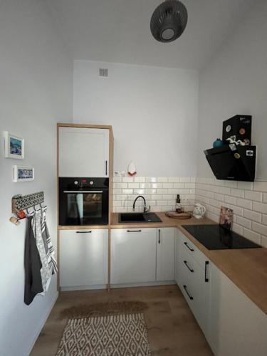 a kitchen with white cabinets and a sink and a refrigerator at Romantic apartment in Ruciane in Ruciane-Nida