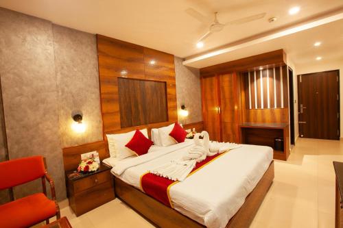 a bedroom with a large bed and a red chair at Hotel Laals Inn Grand By Jesway Hotels and Resorts in Cochin