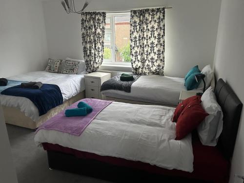 a bedroom with three beds and a window at Family Contractor Modern Home Sleeps 7 Free parking in Grimsby