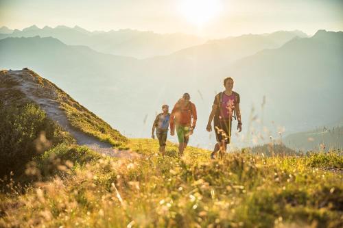a group of three people walking up a hill at Sonnenchalet Bomhuesle in Dalaas
