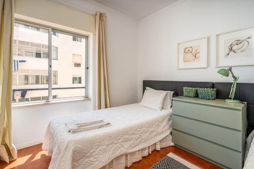 a bedroom with a bed with a dresser and a window at Rocha Beach Apartment in Praia da Rocha