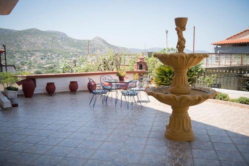 a yellow fountain on a patio with a table and chairs at Irida Suite in Salamís