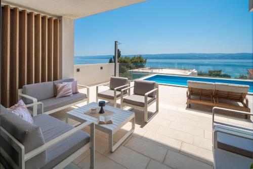 a patio with furniture and a view of a swimming pool at Luxurious VILLA LAPIS - heated pool, sauna, gym and spa, 120m to sandy beach in Omiš