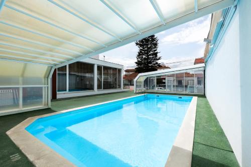 an outdoor swimming pool with a pergola and a house at Spirit Hotel Fonte Real - Antigo Hotel Flora in Monte Real