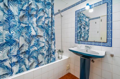 a bathroom with a blue and white shower curtain and a sink at Rocha Beach Apartment in Praia da Rocha
