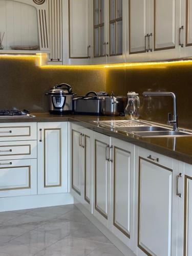 a kitchen with white cabinets and a sink at Vila Dy Bukurite in Draçi