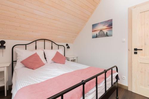 a bedroom with a bed with white and pink pillows at Piekny Domek Koralowy w Lubkowie by Renters Prestige in Lubkowo
