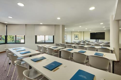 a classroom with tables and chairs and a screen at Hipotels Sherry Park in Jerez de la Frontera