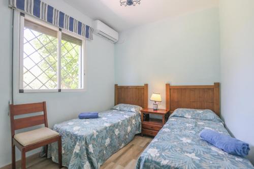 een slaapkamer met twee bedden en een stoel en een raam bij Casa rural Villa Moral in El Arahal
