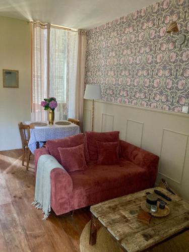 a living room with a red couch and a table at L Henri in Oloron-Sainte-Marie
