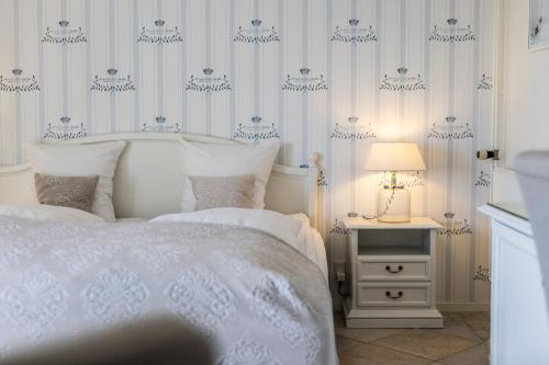 a bedroom with a white bed and a table with a lamp at Fakkelgaarden Hotel & Restaurant in Kruså