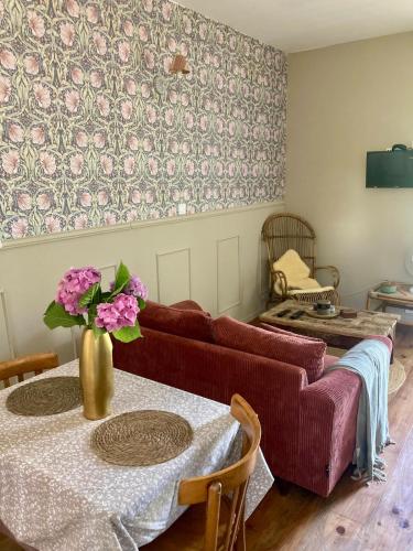 a living room with a couch and a table with flowers at L Henri in Oloron-Sainte-Marie