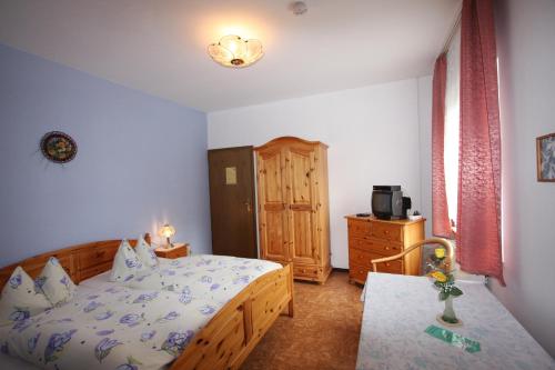 a bedroom with a wooden bed and a dresser and a television at Gasthof & Pension Palmenhof in Leegebruch